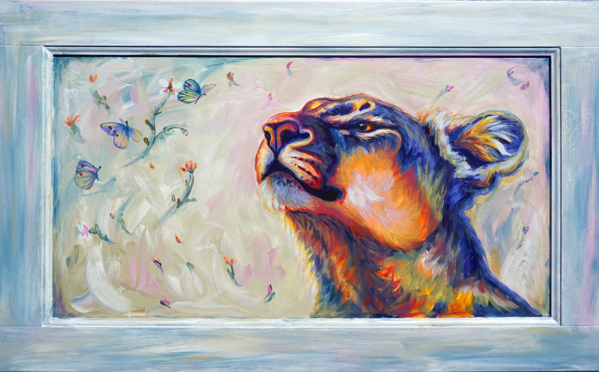 Original painting of a mountain lion looking up at three small flower moths in a soft blush and cream sky, painted on a reclaimed cabinet door